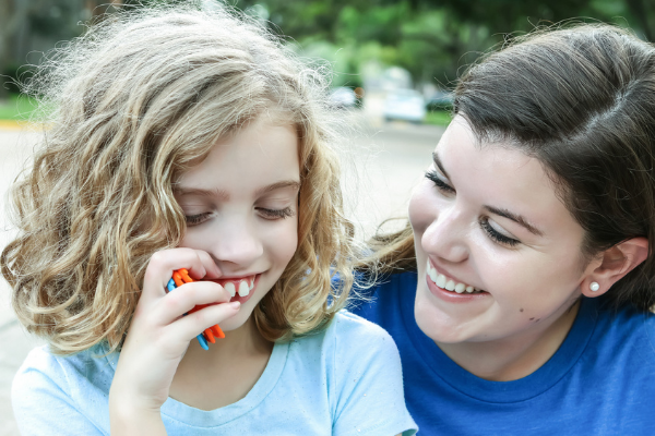 Adult woman with young girl laughing outside