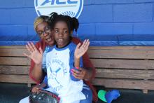 girl and adult in Duke baseball dugout